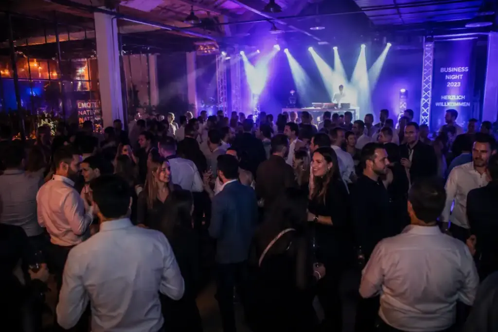 Professioneller DJ auf einem Firmenevent mit tanzenden Gästen und moderner Beleuchtung